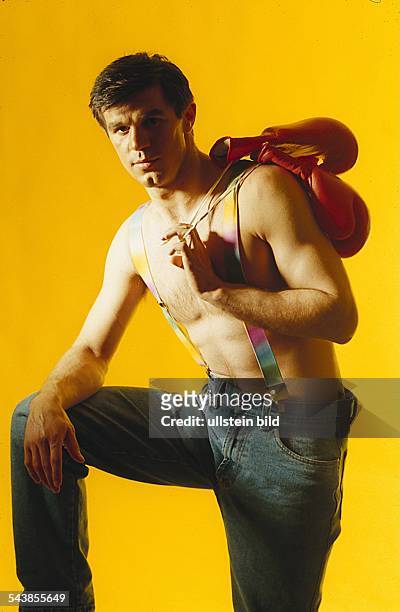 Box-Profi Michael Löwe posiert mit freiem Oberkörper, in Jeans und Hosenträgern für den Fotografen. Seine Boxhandschuhe hat er sich über die Schulter...