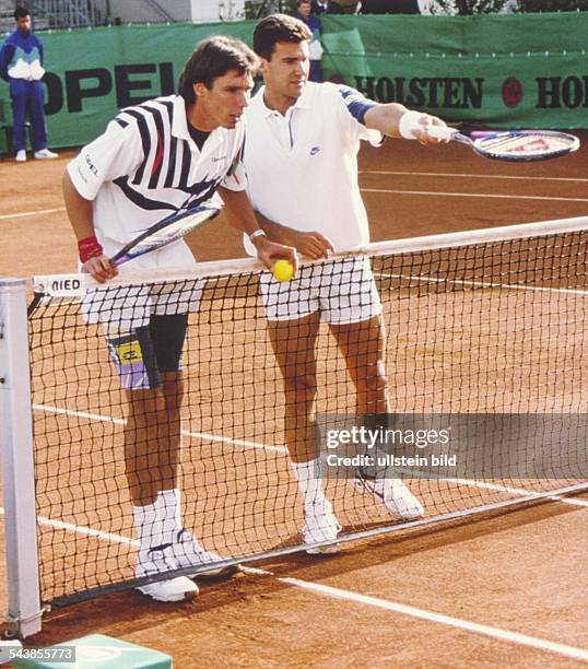 Die Tennisspieler Michael Stich und Carl-Uwe Steeb stehen während der German Open 1992 in Hamburg hinter dem Tennisnetz. Steeb deutet mit seinem...