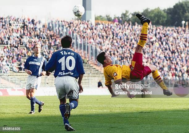 Im Spiel gegen Schalke 04 fliegt Fußballspieler Sean Dundee vom Karlsruher SC bei einem Fallrückzieher durch die Luft. Links von ihm, mit der...