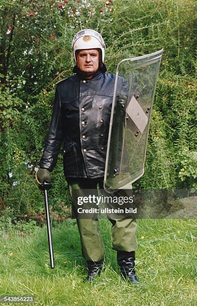 Eine deutscher Polizeiobermeister in Kampfausrüstung mit schwarze Lederjacke, Helm, Schlagstock, und Schild. .