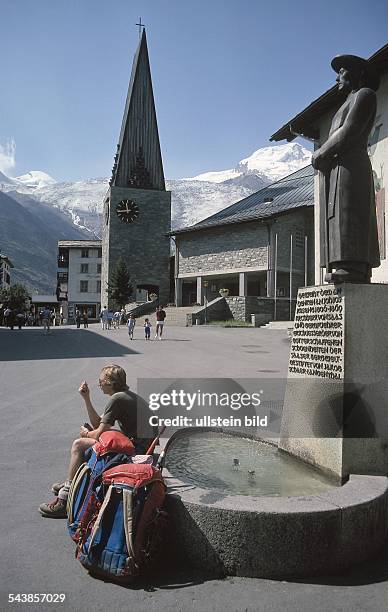 Auf dem Dorfplatz von Saas Fee schmückt eine Statue, die den Pfarrer Imseng zeigt, einen Brunnen. Imseng gilt als Begründer des Tourismus im Saastal....