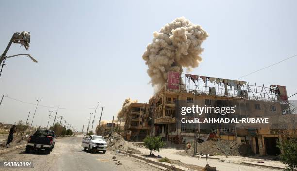 Smoke rises in the city of Fallujah on June 30, 2016 as Iraqi forces destroy a booby-trapped building after they've recaptured the city from Islamic...