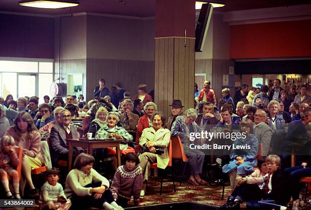 New arrivals, wet from the rain, gather in the bar for instructions at Butlins Holiday camp in Skegness. Butlins Skegness is a holiday camp located...