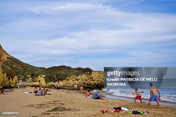 People sunbath and play games on Santa Eulalia beach at Albufeira, Loule, southern Portugal on June 10, 2016. Instability and violence in the...