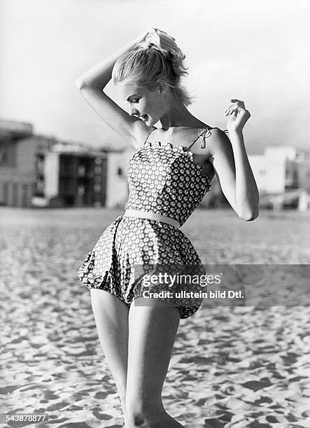 Beach fashion: Model dressed in a short trousers costume with shoulder straps on the beach - ca. 1957- Photographer: Regine Relang- Published by:...