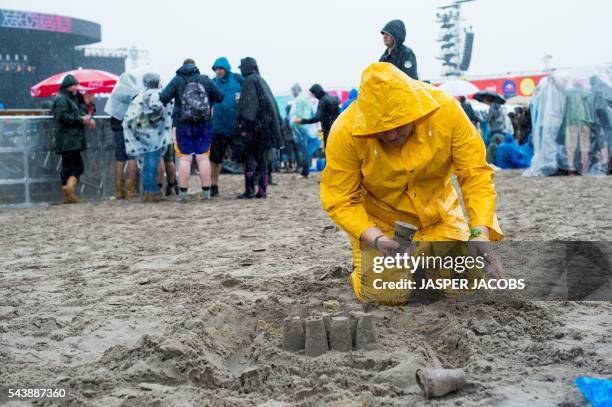 Man wearing a raincoat play with sand during the first day of the Rock Werchter music festival on June 30, 2016 in Werchter. / Belgium OUT