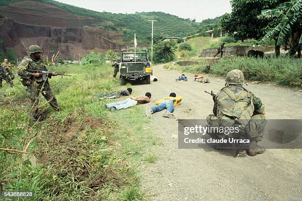 Soldiers survey prisoners during the US invasion of Grenada. | Location: Grenada.
