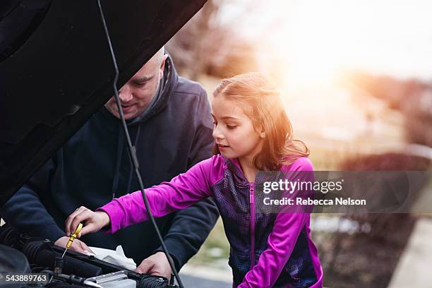 father and daugher checking oil in car