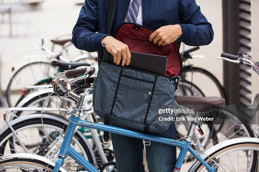Man with bicycle putting laptop into courier bag