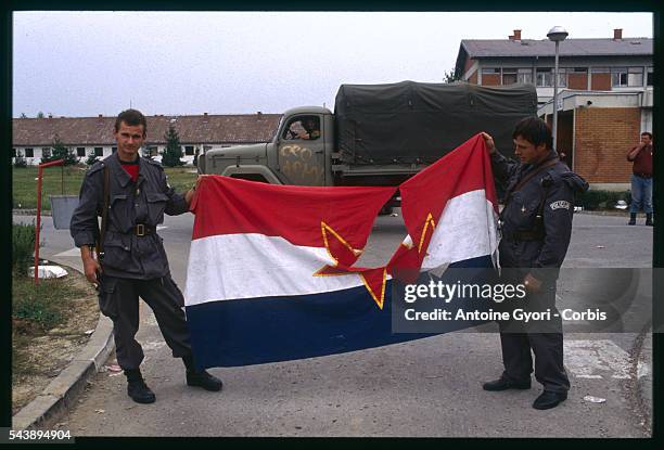 Two Croatian soldiers hold a Yugoslavian flag bearing a hole in the center, after fights against the Yugoslavian army and the Serbian militias,...