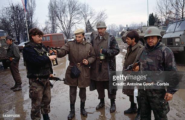 Serbian fighters drink wine and smoke cigarettes among the ruins of Vukovar after a three-month battle between the Croatian armed forces and the...