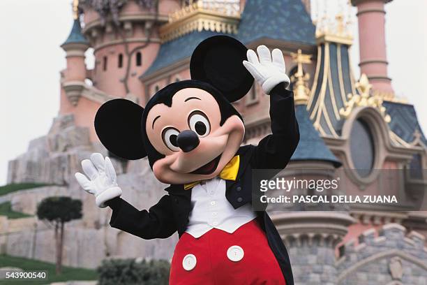 Mickey Mouse in front of the Sleeping Beauty Castle at Disneyland Resort Paris.