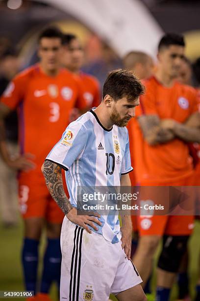 Argentina forward and captain Lionel Messi waits to take his 2nd place medal while Chile defender Enzo Roco and Chile midfielder Pablo Hernandez look...