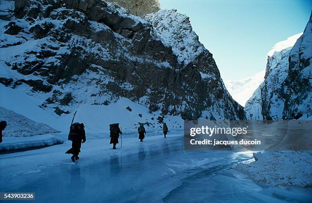 Local inhabitants walk the frozen surface of the Zanskar River.