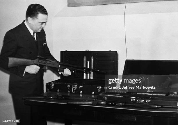 Director J. Edgar Hoover reviews weapons.