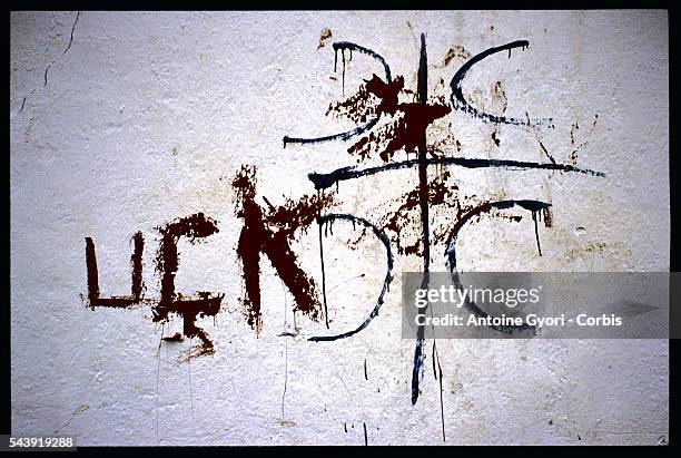 Graffiti covers the serbian symbol on a wall.