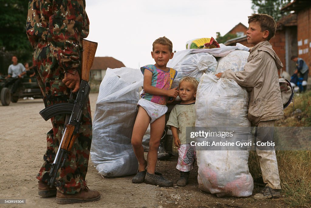 Kosovar Guerrilla Standing by Young Children