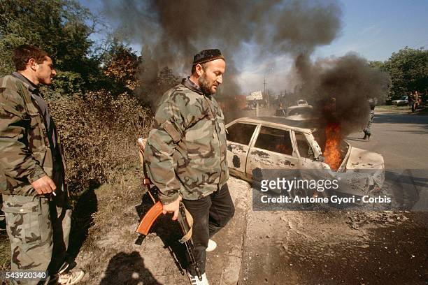 Chechen soldiers walk past a burning car following a Russian bombardment in the capital.