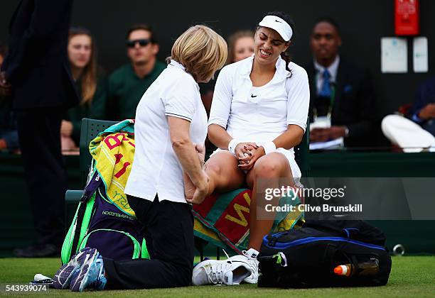 Ana Konjuh of Croatia receives treatment on her ankle during the Ladies Singles second round match against Agnieszka Radawanska of Poland on day four...