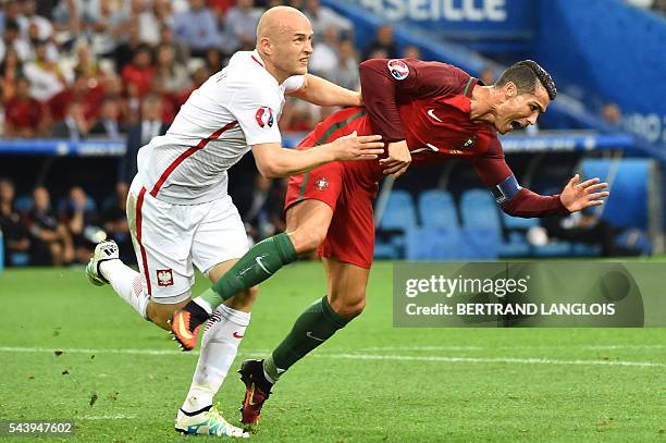 Portugal's forward Cristiano Ronaldo and Poland's defender Michal Pazdan fall during the Euro 2016 quarter-final football match between Poland and...