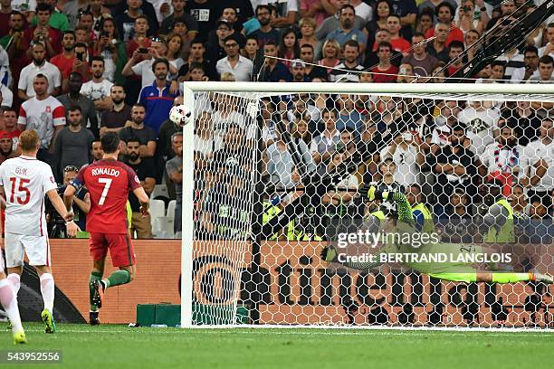 Poland's goalkeeper Lukasz Fabianski dives for the ball next to Portugal's forward Cristiano Ronaldo during the Euro 2016 quarter-final football...