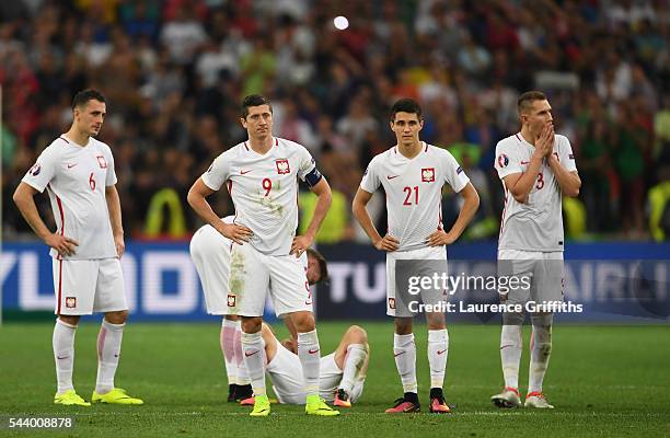 Tomasz Jodlowiec, Robert Lewandowski, Cedric Soares and Pepe of Portugal show their dejection after their defeat through the panelty shootout in the...