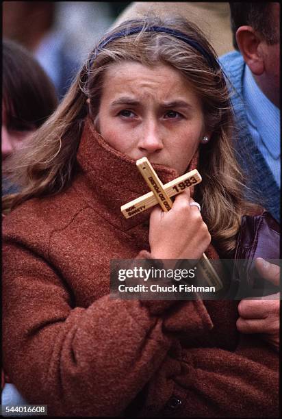 View of an unidentified woman with a souvenir wooden cross as she attends Pope John Paul II's Mass, Poland, mid June 1983.