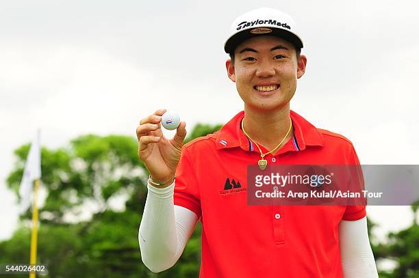 Jazz Janewattananond of Thailand poses with his golf ball after making the hole-in-one during the round 2 of the Yeangder Tournament Players...