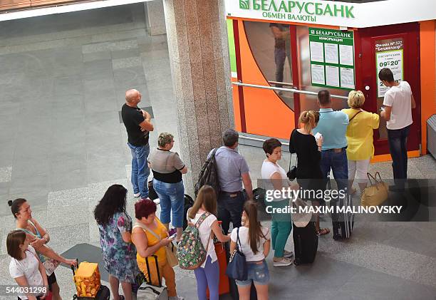 People queue up to change money at the currency exchange office of the Belarus bank at the railway station in Minsk on July 1, 2016. Belarus is...