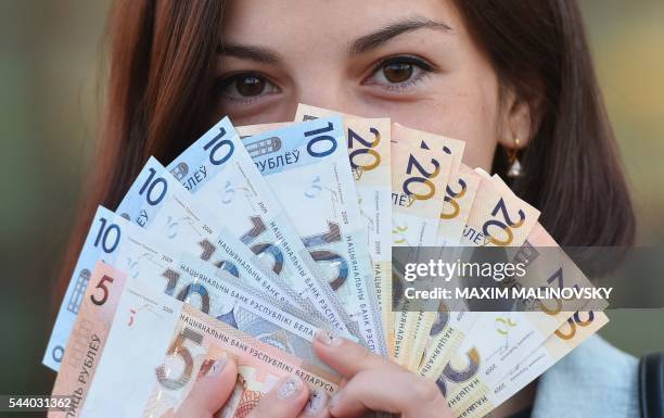 An employee holds bank notes at a fast food restaurant in Minsk on July 1, 2016. - Belarus is slashing four zeros from banknotes, the central bank...