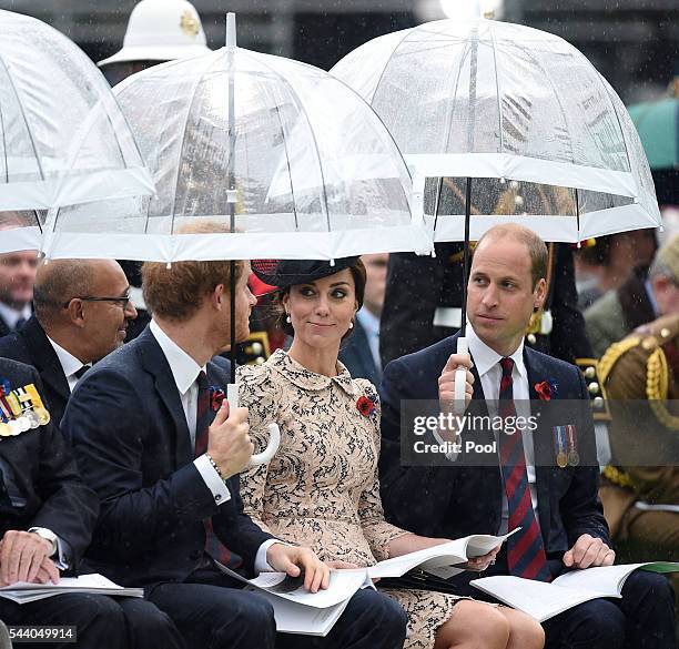 Prince Harry, Catherine, Duchess of Cambridge and Prince William, Duke of Cambridge shelter under umbrellas during the Commemoration of the Centenary...