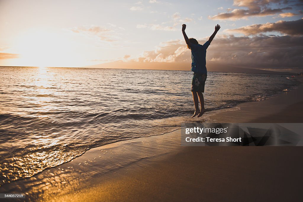 Boy is Jumping along Ocean in Maui, Hawaii