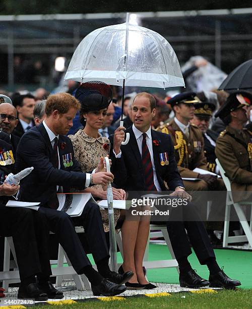 Prince Harry, Catherine, Duchess of Cambridge and Prince William, Duke of Cambridge shelter under umbrellas during the Commemoration of the Centenary...