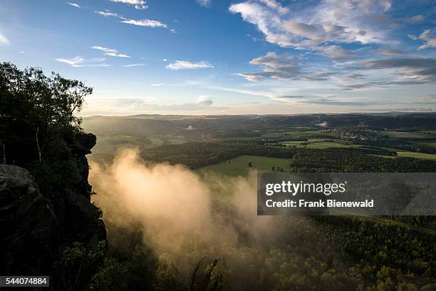 Fog is arising over the hills of Elbsandsteingebirge, seen from Lilienstein in the last light of the day.