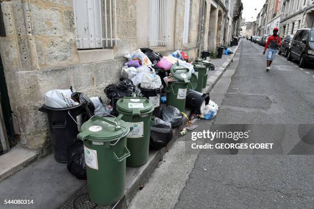 Man walks past trash covering the sidewalk on July 1, 2016 in Bordeaux, southwestern France. - The "blonde" city, elected first tourist destination...