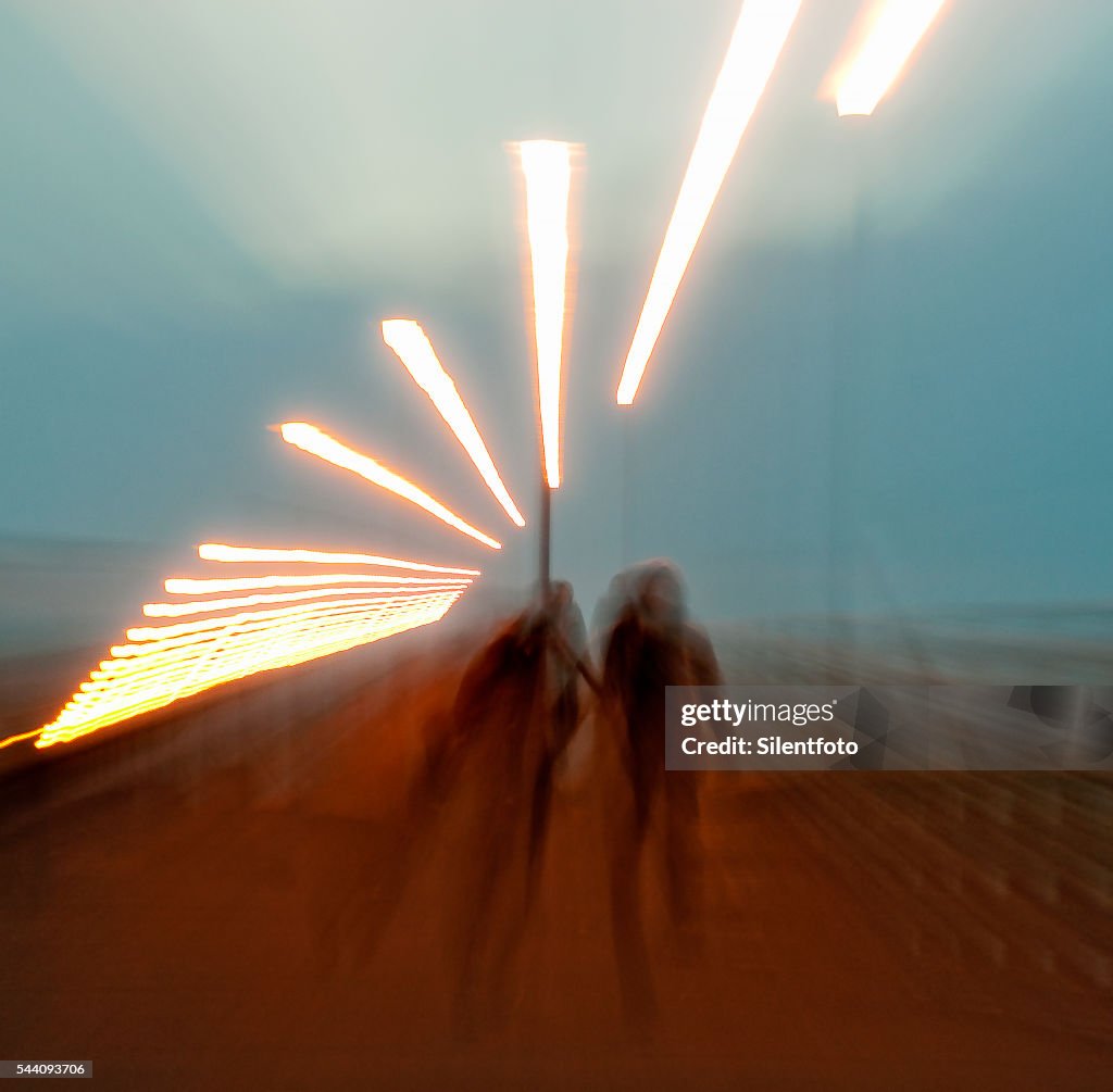 Zoom Out on Two Figures walking Along A Pier