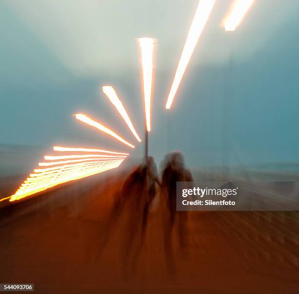 zoom out on two figures walking along a pier - zoom out stock pictures, royalty-free photos & images