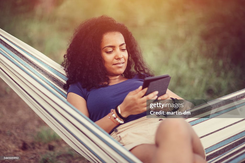 Giovane ragazza in un amaca con e-book