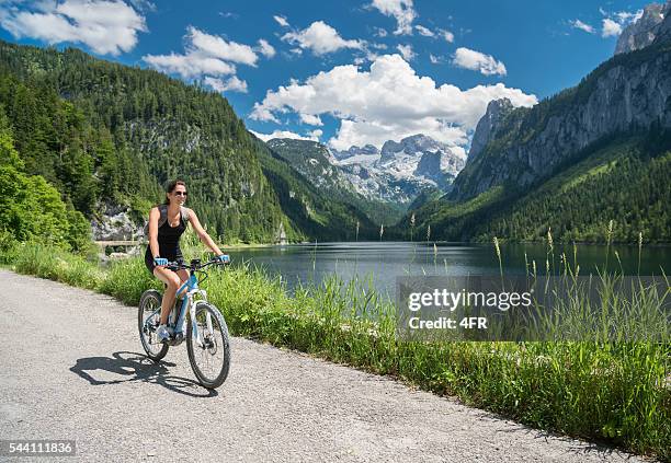 mulher em e-bike mountainbike na natureza, lago gosau, geleira dachstein - salzkammergut - fotografias e filmes do acervo