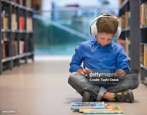 schoolboy with headphones and tablet computer in library - school tablet stockfoto's en -beelden