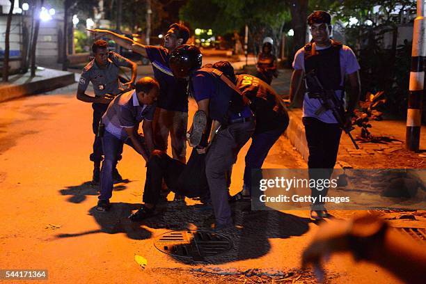 An injured man receieves help after an attack at a restaurant in the early hours of July 2, 2016 in Dhaka, Bangladesh. Gunmen have taken at least 20...