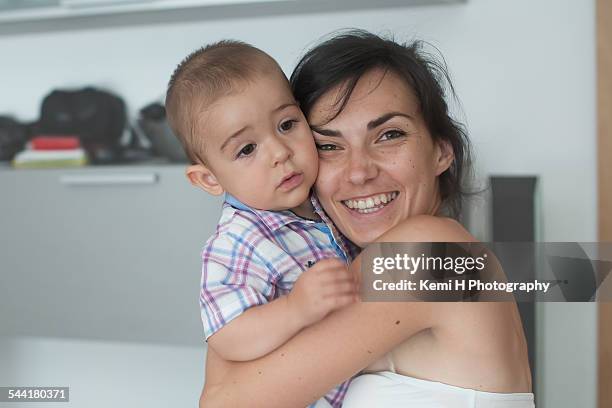 smiling mother hugging her boy home - big hug stock pictures, royalty-free photos & images