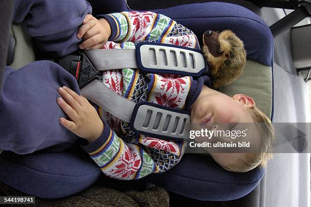 Kleiner Junge schläft im Kindersitz eines Autos- 2004