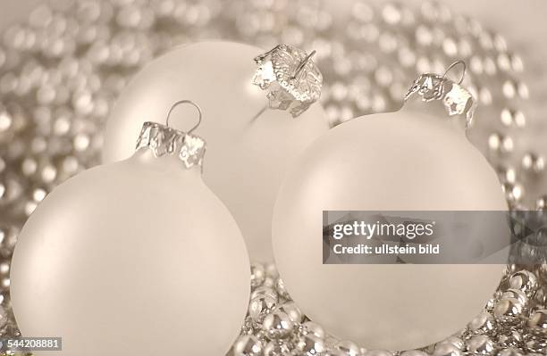 Drei Weihnachtskugeln auf silberner Kette arrangiert.