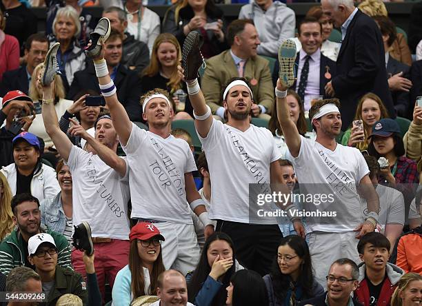 Fans of Marcus Willis of Great Britain hold their shoes up during his second round match against Roger Federer of Switzerland at Wimbledon on June...