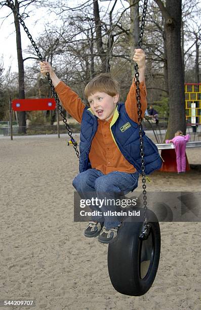 Spielplatz im Zoologischen Garten. Junge auf einer Schaukel mit Reifen