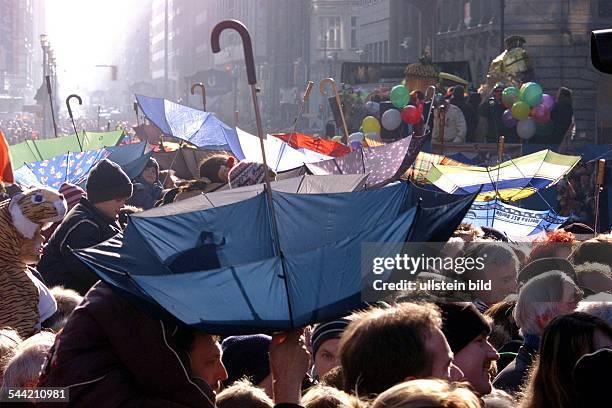 Deutschland, Berlin - Mitte: Karnevalsumzug Unter den Linden. Zuschauer mit umgedrehten Schirmen fangen Kamelle