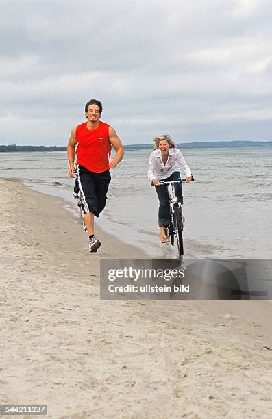 Frau fährt Rad, Mann joggt am Strand von Binz, Mecklenburg-Vorpommern-