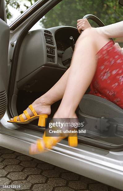 Deutschland, Verkehrssicherheit: Junge Autofahrerin mit hochhackigen Sommerschuhen vor dem Antritt einer Autofahrt,