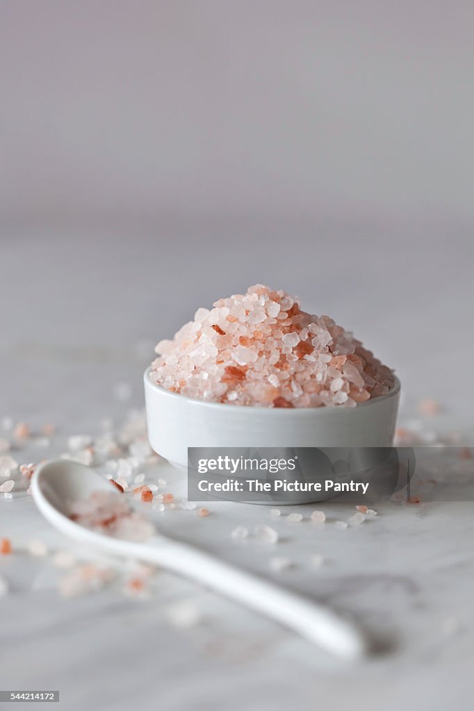 Pink Himalayan salt in the small white bowl and white marble surface